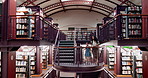 Woman, girl and stairs in library for books on information, learning and knowledge for education. Student, tutor and walking on steps for studying, research and bookstore for child development