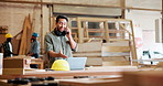 Phone call, carpenter and man in workshop on laptop for maintenance, remodeling and construction business. Factory, furniture and person on smartphone for contact, talking and chat for online order