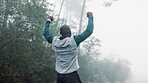 Celebration, running and man in forest for fitness, training and excited with hand, fist and energy. Nature, runner and healthy male person in woods for workout, trees and win for athlete with muscle