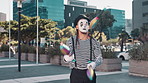 Juggling, mime and man in city for performance, entertainment and creative act in urban town. Street performer, theatre and person with pins juggle for festival, carnival and circus in costume
