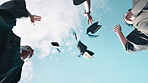 Happy people, students and celebration with graduation caps in air for winning or achievement below blue sky. Low angle or group of graduates with high five or throwing hats for success in nature