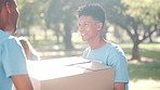 Excited man, volunteer and box with team in nature for service, charity or outdoor support at park. Happy male person or young coworker with smile and taking parcel, stock or package for donations 