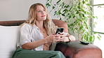 Woman, smartphone and break with thinking, relax and rest at home or apartment living room. Lady, window and technology for social media, message and browse or texting for happiness on sofa in lounge