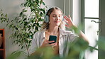Woman, headphones and break with music, relax and rest at home or apartment living room. Lady, window and smartphone for podcast, radio and online audio and internet for happiness on sofa in lounge