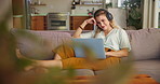 Laptop, headphones and student on sofa in home typing online for remote or distance learning. Technology, assessment task and female person on couch in a house for elearning, studying or development