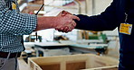 Handshake, agreement and industry engineers in workshop for partnership, deal or negotiation. Greet, woodwork and closeup of foreman shaking hands with carpenter for onboarding in factory warehouse.