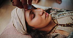 Holistic, crystal and woman healing with stone on face for indigenous meditation or relax with peace. Spiritual, reiki and person with rock from healer on mind chakra to detox for wellness and zen