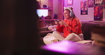 Headphones, woman and play video game on sofa in home for online competition. Controller, girl and person on console technology for entertainment with neon light in apartment at night in living room