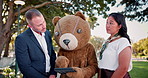 Business people, tablet and discussion of group outdoor at park in funny teddy bear costume. Technology, meeting and teamwork of consultants planning, brainstorming or strategy with mascot in garden