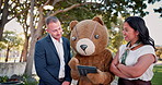 Business people, tablet and discussion of happy group outdoor at park in funny teddy bear costume. Tech, meeting and teamwork of consultants planning, brainstorming or strategy with mascot in garden