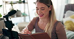 Woman, influencer and recording with writing, notes and planning for episode of vlog in home living room. Girl, phone and microphone for live streaming with smile, notebook and ideas on social media