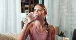 Woman, drinking water and hydration after home exercise, workout in living room with liquid for health and wellness. Fitness, training and thirsty athlete with pilates or yoga, power and challenge