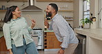 Couple, dancing and singing in kitchen with spoon, smile and together for comic performance in home. Woman, man and playful with utensil microphone for funny game, music or happy for karaoke in house