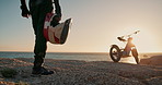 Closeup, helmet and man with motorbike, sand and nature with sunshine and travel with transport. Person, rider and dune with extreme sport or safety with gear and protection with freedom or challenge