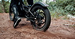 Person, dirt bike and feet on forest trail with tyre spin, speed and start with dust for adventure. Motorcycle, rider and ready for race, transportation or journey with shoes on ground path in woods