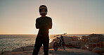 Biker, man and relax at sea for sunset with arms crossed, confidence and travel adventure with helmet. Motorcycle, person or rocks with break from road trip with sunrise and morning horizon at ocean
