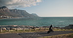 Person, road and ride with electric bicycle by ocean coast for scenic route or view of outdoor nature. Rider cycling on street with helmet by the beach, water or mountain for travel on mockup space