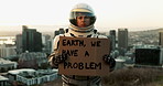 Astronaut, city and board with sign for message, alert or signal of news or problem on planet earth. Portrait of space traveler showing billboard or notification for crisis, awareness or protest