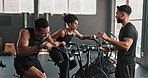 Health, instructor and bicycle in gym for exercise, high five in training class for body wellness with workout goal. Coach, cardiovascular fitness or joint mobility, client progress and gym equipment