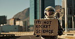 Astronaut, city and billboard with sign for message, alert signal of news or note to people on earth. Space traveler showing board or notification for crisis, awareness or protest in an urban town