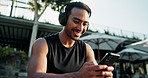 Man, headphones and smartphone with happy athlete, relax and searching online for music or podcast for workout. Wellness, typing or listening or audio for sports training, runner on exercise break
