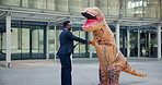 Inflatable dinosaur costume, man and outdoor for team building with tablet, handshake and mascot. Businessman, employee and tech for humor in business precinct for collaboration, staff and morale