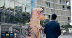 Inflatable dinosaur costume, man and outdoor for team building with tablet, handshake and mascot. Businessman, employee and tech for humor in business precinct for collaboration, staff and morale