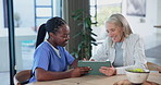 Senior woman, tablet and medical support with caregiver with cardiovascular consultation. Tech, digital and nurse with hospital exam feedback with conversation and discussion of health and wellness