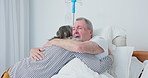 Senior couple, support and hug sick husband in hospital for love, care or kindness. Comfort, man and woman embrace in clinic for empathy, visit and healthcare for cancer surgery rehabilitation in bed