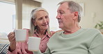 Senior, couple and cheers with coffee on sofa for bonding, retirement and conversation in living room of home. Elderly people, hot beverage and laughing on couch with relax, wellness or morning break