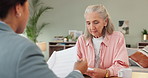 Senior, woman and talking to financial advisor in home with mortgage, paperwork and consultation. Mature, person and questions for contract and help investing in property or review taxes in document