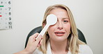 Woman, reading and eye test with optometrist in office, vision or eyesight for glasses with optician holding occluder. Healthcare, sight examination in cover uncover, assessment for ocular deviation