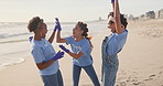 High five, volunteer and team of women, beach and gloves for recycling, waste and outdoor in nature. Collaboration, group and female people, ready and helping environment, cleaning and litter in sea