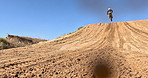 Sport, motorbike and person driving in desert, sand or jump on hill for off road stunt on path. Dirt, trail and driver travel on motorcycle with skill, technique and moto adventure in countryside