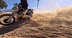 Sport, motorbike and sand in wheel from desert driving and person with off road stunt on hill. Dirt, trail and fast driver travel on motorcycle with skill, technique and moto adventure in countryside