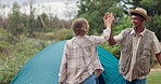 Camping, happy couple and high five at tent in nature on holiday, vacation and interracial people travel outdoor. Setup, man and woman at campsite together for adventure or celebrate in the woods