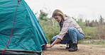 Woman, hammer and camping with tent outdoors, nature and survival or adventure with shelter setup for people. Tie, guy line for safety to ground, trekking in Russian with female person and travel
