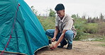 Man, campsite and camping with tent outdoors, nature and survival or adventure with shelter setup for people. Vacation, guy line for safety to ground, stake and hammer in Russian to travel journey
