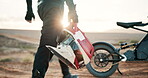 Person, motorbike and helmet outdoor adventure for extreme sports challenge, performance or motor cross. Driver, walking and transportation journey or off road activity in desert, speed or adrenaline