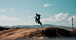 Jump, motorbike and man in air or outdoor training for extreme sports, safety and practice on sand. Sky, risk or fearless driver flying with motorcycle for off road race, hill or trick in challenge