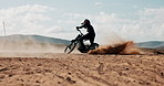 Biker, sand and man spinning motorbike in outdoor training and safety for extreme sports and practice in desert. Fun, dirt and driver on motorcycle for dunes, dust or donuts in performance on holiday