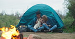 Fire, kiss and couple camping with dog in forest for travel, adventure or bonding in nature together. Sustainable living, flame and off grid people with pet in jungle for backpacking, fun or journey