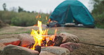 Fire, nature and camping wood with tent with heat and flames in the outdoor park. Adventure, field and holiday in a campsite with smoke, burning and pit for cooking on ground with grass at morning