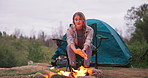 Fire, woman and camping wood with flames for heating hands and eco holiday in nature with a tent. Adventure, field and rocks in a campsite with smoke, burning and pit with travel and relax in a park
