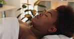 Black woman, face or sleep in spa, treatment or skincare as health, wellness or dream of zen massage. Client, eyes closed or towel on bed as luxury, holistic or retreat to detox, relax or self care