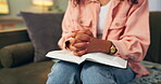 Person, hand and bible praying in home with Christianity religion as worship, study or Jesus. Fingers, book and couch for God belief or spiritual support with holy spirit healing, christ or guidance