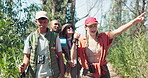 Friends, hiking and pointing at forest view, people travel for sightseeing and environment with tourism. Nature, adventure together and friendship group walking outdoor with weekend trip for bonding