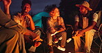 Camping, marshmallow and friends with fire at night in nature for holiday, vacation and adventure. Campsite, travel and men and women talk by bonfire for bonding, social gathering and relax outdoors