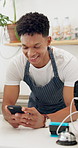 Happy man, barista and typing with phone at cafe for social media, communication or conversation at coffee shop. Male person, waiter or employee with smile on mobile smartphone at indoor restaurant