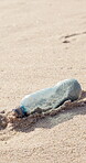 Plastic bottle, dirt and beach sand for pollution, environmental crisis and earth day awareness in closeup. Garbage, trash and waste management by the ocean for recycle, NGO and eco friendly project